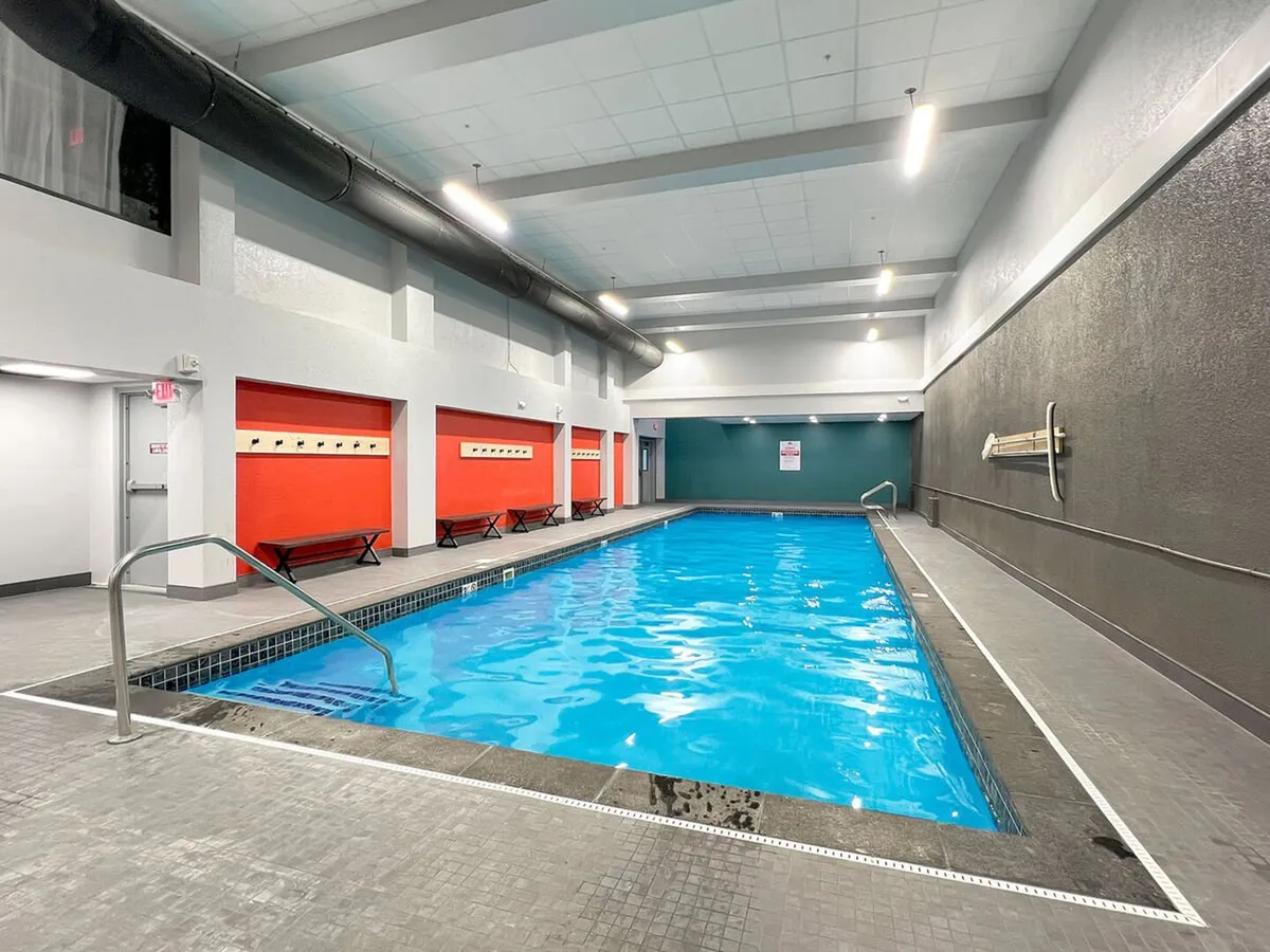 A bright, modern indoor pool area with vibrant red lockers and sleek lighting. The swimming pool invites relaxation and post-ski rejuvenation, aligning with amenities like the indoor pool, hot tub, and steam room described in the content.