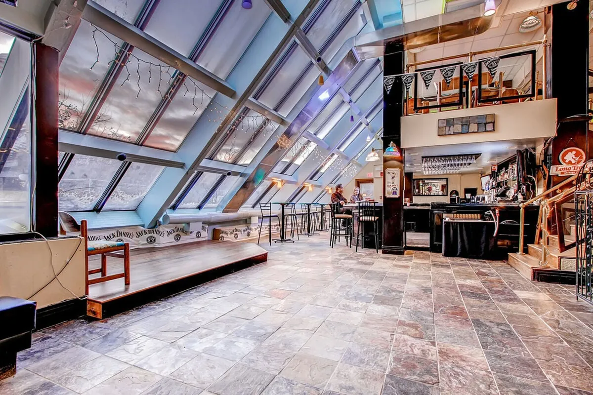 This lively bar and casual dining area features large glass windows, a welcoming bar setup, and flexible seating arrangements. The ambiance is communal and upbeat, suggesting an alternative for guests seeking a break from cooking with onsite dining options.