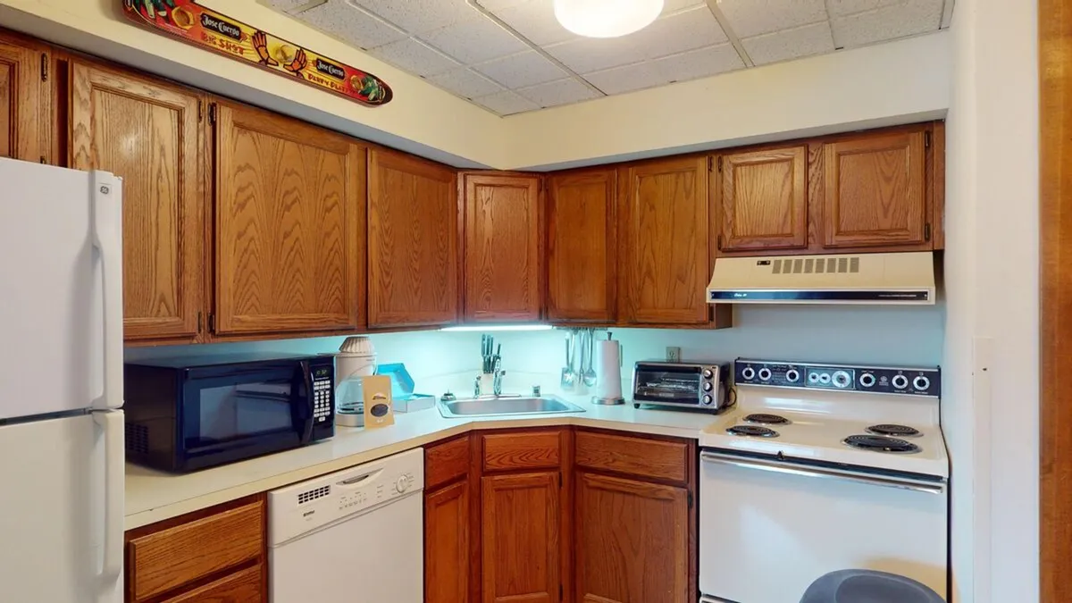 Featuring a similar style of wood cabinetry and ample countertop space, this kitchen image highlights the modern appliances and easy workflow between cooking and socializing areas. The warm ambiance and layout suggest it's ideal for sharing recipes and hosting meals.